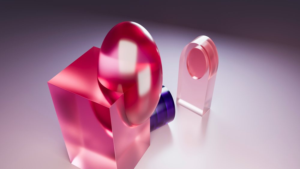 Abstract digital artwork showing transparent geometric shapes including a pink cube, oval shape, purple cylinder, and rectangular arch on a reflective surface in a minimalist studio.