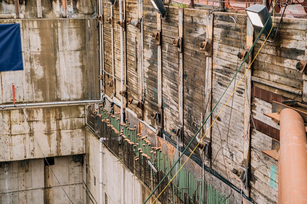 A construction site showing concrete and wooden retaining walls with steel reinforcements and industrial cables, tunnel boring machine, tunnel, drilling, USA.