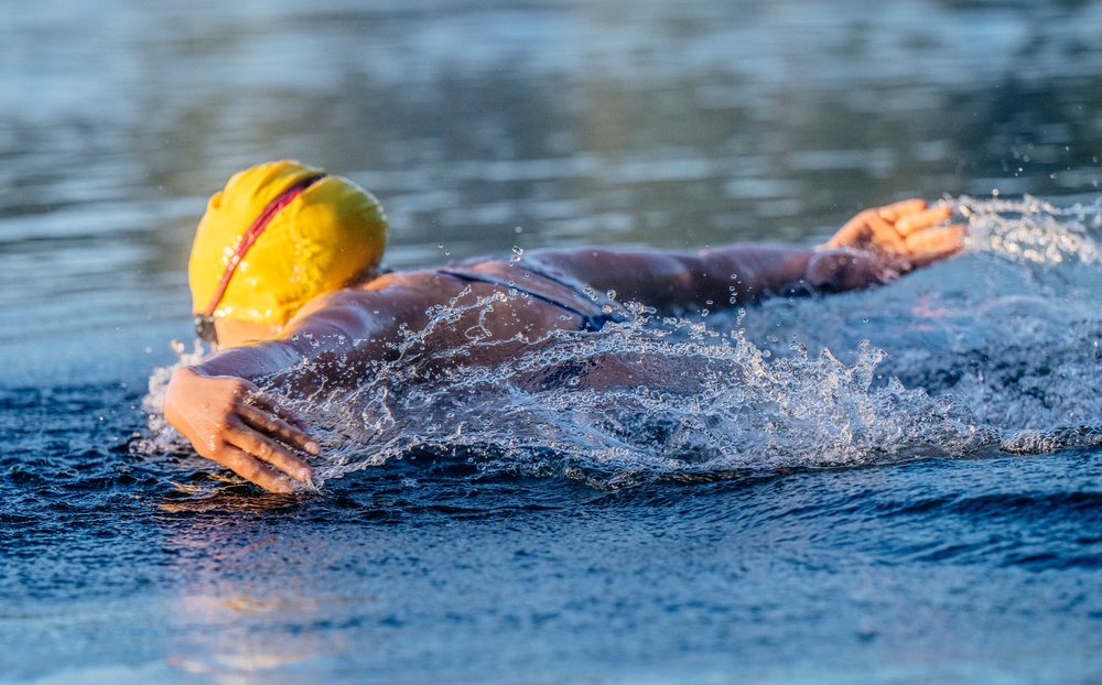 Swimmer wearing a yellow swim cap performing a stroke in open water, USA.