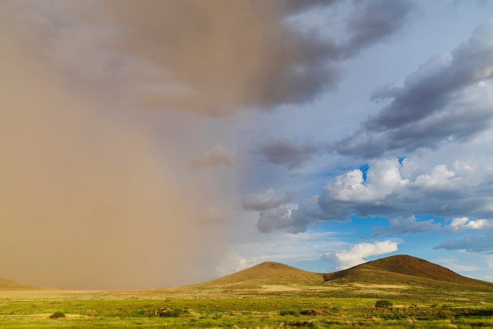 Haboob Dust Storm advances over grassy hills and grassland under a cloudy sky, Storm Chasing, Weather, Environmental Issues, Rodeo, Arizona, USA.