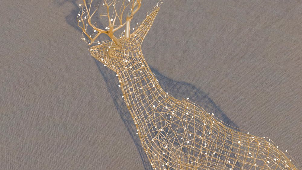 Wireframe deer sculpture with attached decorative lights casting a shadow on a textured surface in an indoor environment.
