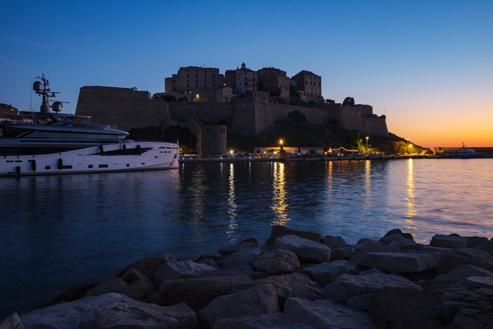 Early morning view at Dawn of the medieval Citadel overlooking a Yacht moored in Calvi harbor, Travel Photography, Corsica, France.
