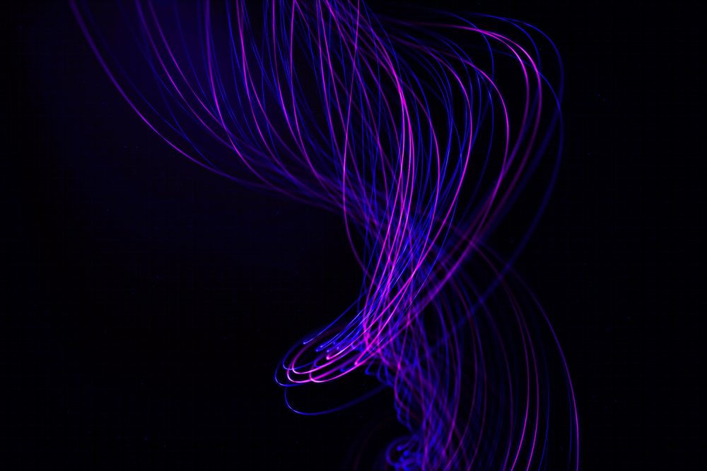 Curved purple and blue light trails form an abstract glowing pattern against a dark background.