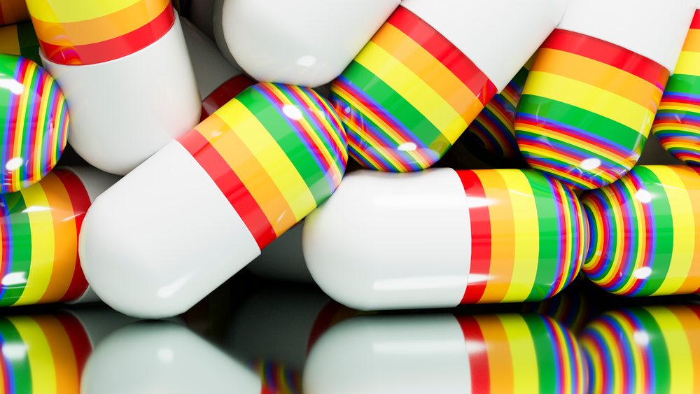 Close-up of white capsules with rainbow-colored stripes reflected on a glossy surface.