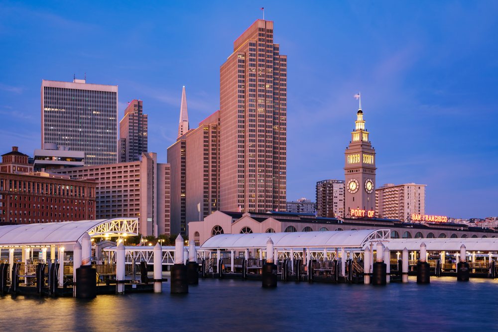 Port of San Francisco waterfront clock tower and city skyline at dawn reflecting on calm harbor waters, landscape, cityscape, city life, California, USA.