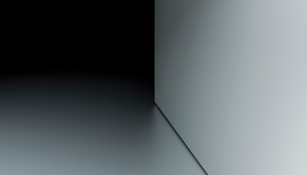 Minimalist abstract corner showing two intersecting grey and black surfaces creating geometric shadows and contrast.
