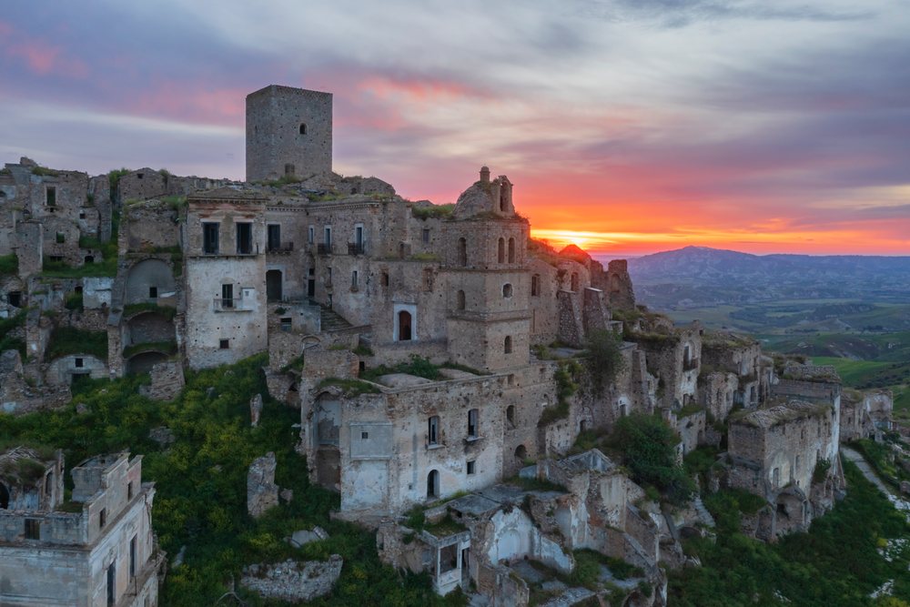 Ruined City of Craco on a hilltop at Sunrise with ancient stone buildings and lush greenery, Basilicata, Italy.