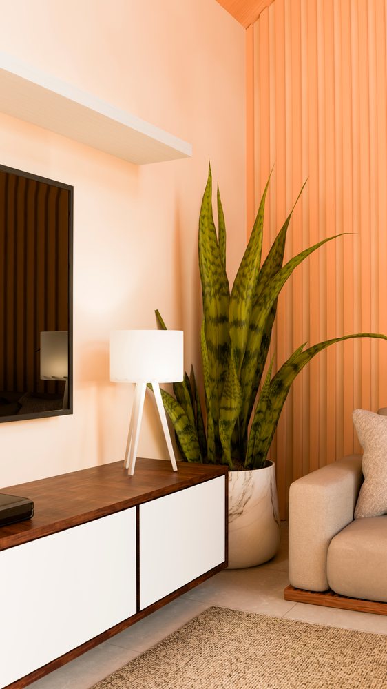 Snake plant in a white pot beside a beige sofa and wooden cabinet with a floor lamp in a modern living room.