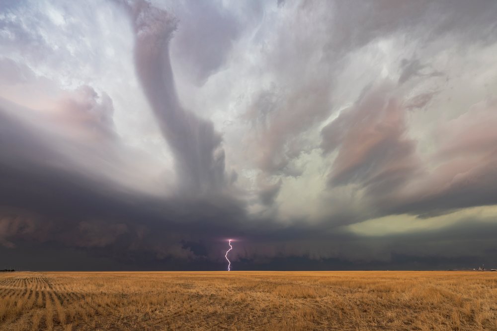 Supercell thunderstorm with visible tornado funnel and lightning strike over dry grassy plains in Tornado Alley, Storm Chasing, Weather, Environment, Tribune, Kansas, USA.