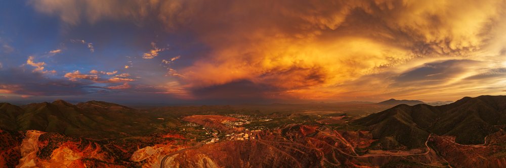 Aerial view at Dusk of the Bisbee copper open pit mine and surrounding mountains under dramatic storm clouds, Storm Chasing, Weather, Environmental Issues, Arizona, USA.