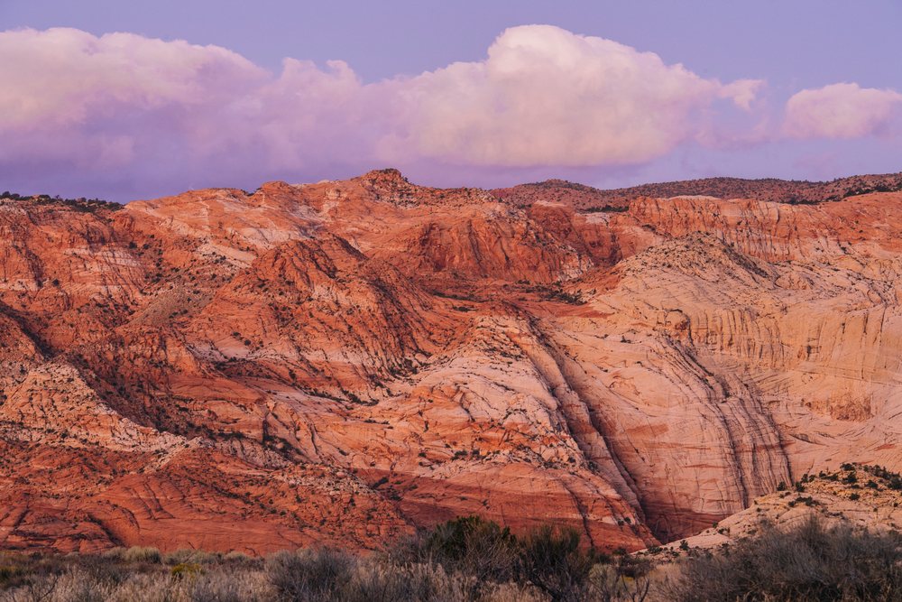 Red rock formations and rocky hills with scrub vegetation under a twilight sky, Snow Canyon, red Cliffs Desert, Utah, USA.