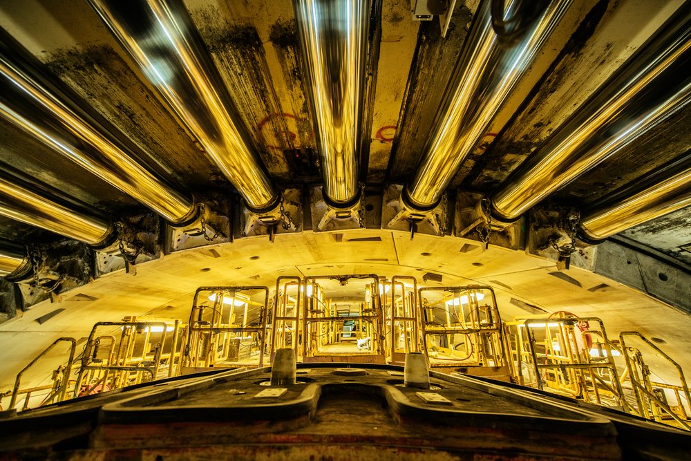 Interior view of a tunnel boring machine with metal pipes and yellow industrial lighting in an underground construction site, a tunnel boring machine, drilling, USA.