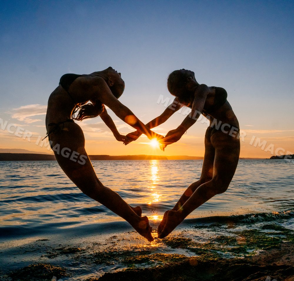 Two women practicing partner yoga acrobatics at beach sunset in wa USA