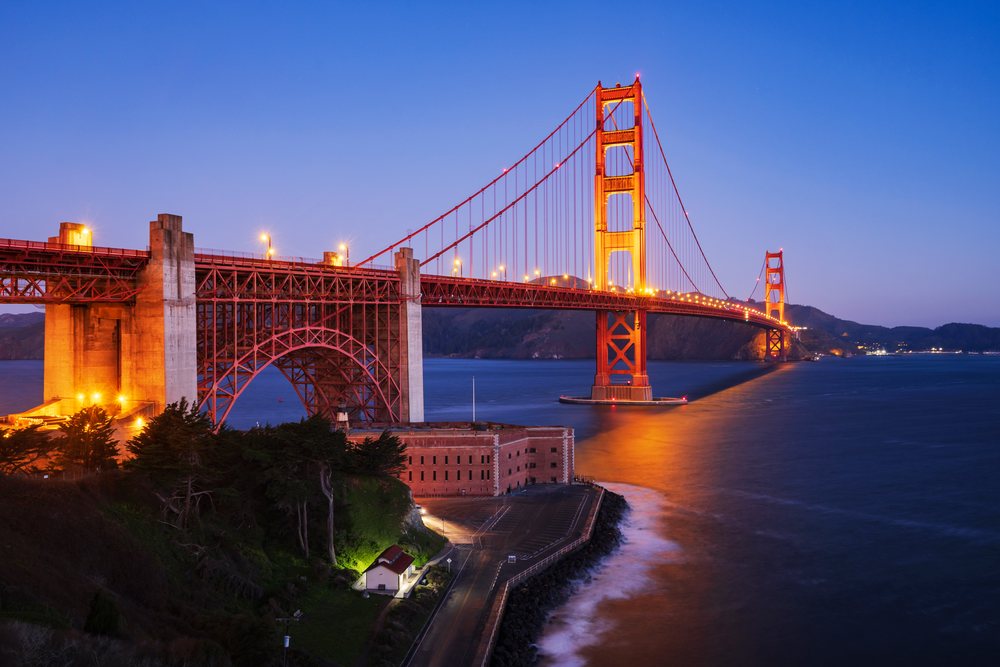 Golden Gate Bridge illuminated at Dawn spanning San Francisco Bay with water and cityscape, landscape, city life, California, USA.
