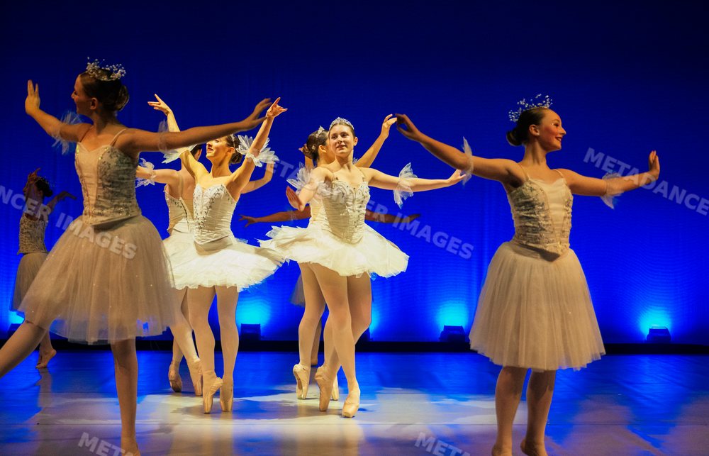 Ballerinas perform a holiday ballet in elegant white tutus on stage