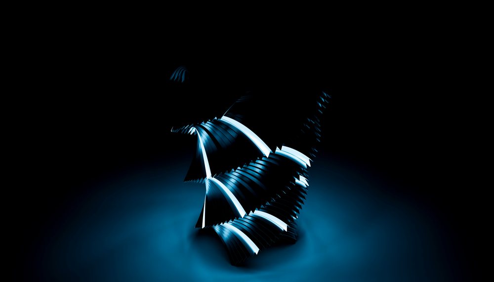 Abstract metallic sculpture composed of curved segments illuminated with blue light against a dark background in a studio setting.