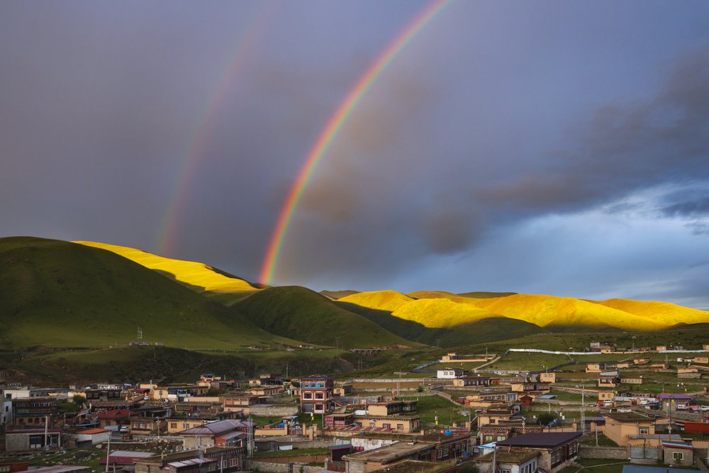 Double rainbow over green hills and village at Sunset, Zhuqing, Sichuan Province, People's Republic of China.