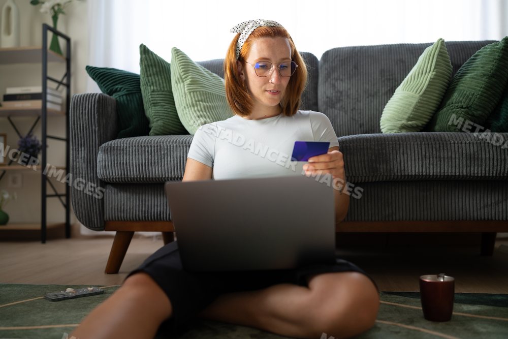 A white woman uses a laptop and credit card for online shopping