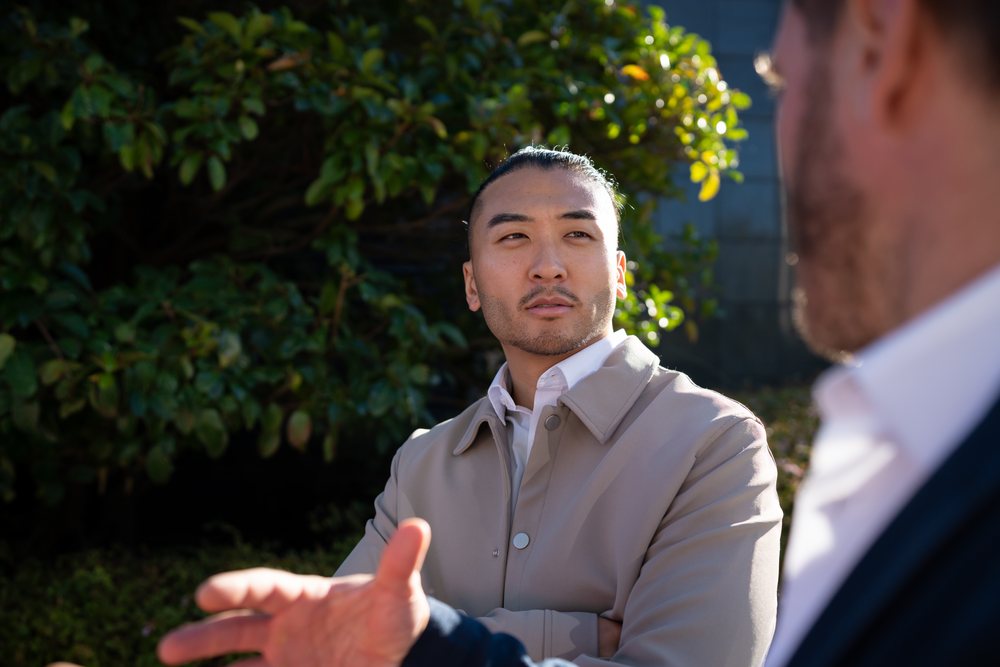 Man with a bun listens attentively during an outdoor conversation, Madrid, Spain.