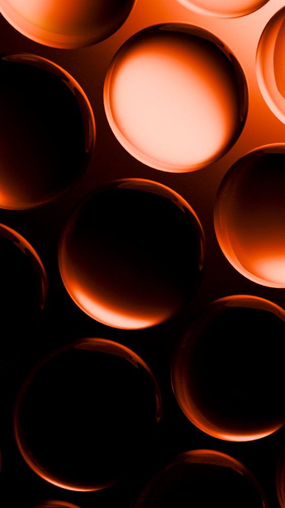 Orange glowing glass spheres arranged abstractly against a dark background create an illuminated artistic pattern.