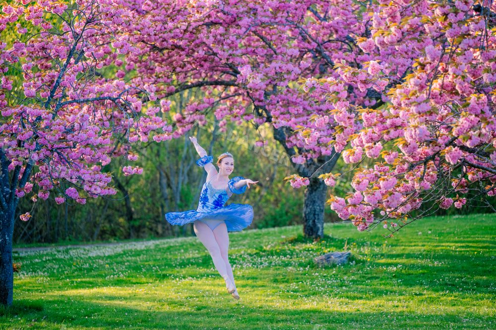 A ballet dancer gracefully leaps outdoors