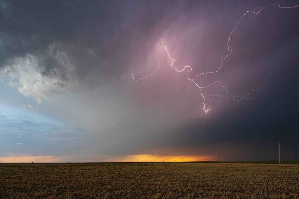 Lightning strikes amid Storm clouds over a rural field with power lines, Storm Chasing, Weather, Environment, Ulysses, Kansas, USA.