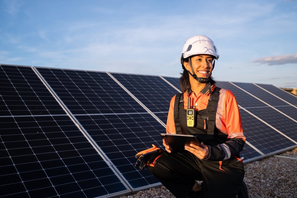 Smiling solar technician woman holds a tablet near solar panels outdoors at a renewable energy site, Madrid, Spain.