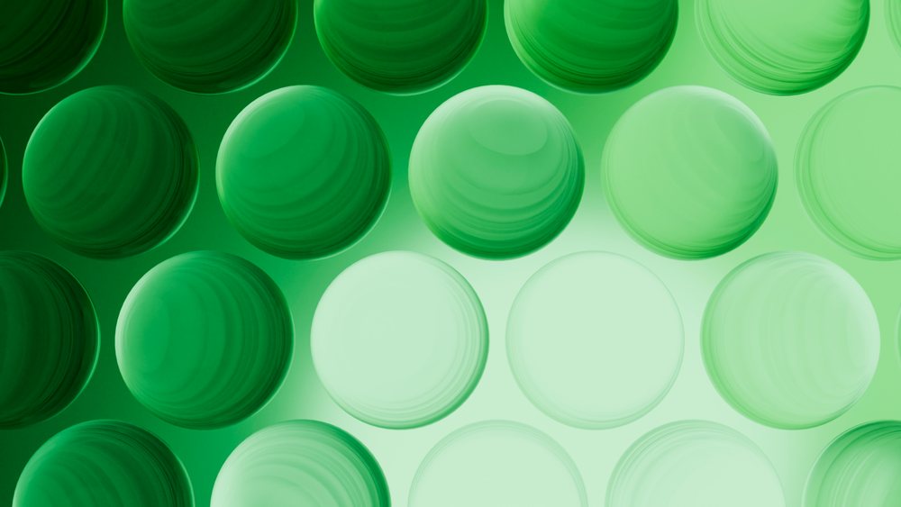 Digital illustration showing a repeating pattern of green transparent spheres with smooth surfaces and light gradients.