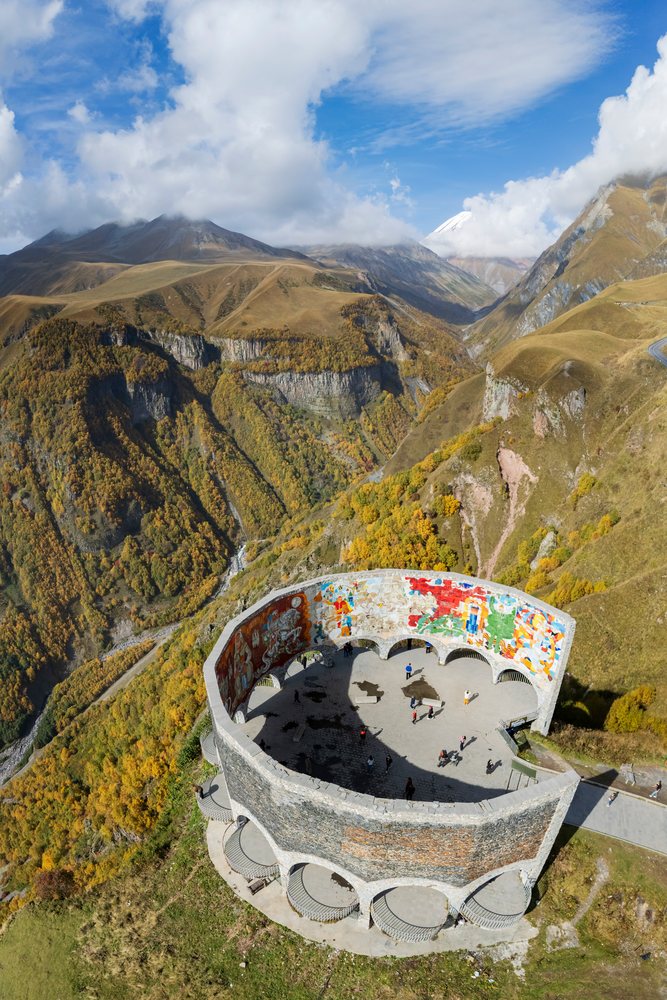 Russia-Georgia Friendship Monument with colorful murals overlooks Autumn mountains and valleys, Gudauri, Mtiuleti Region.