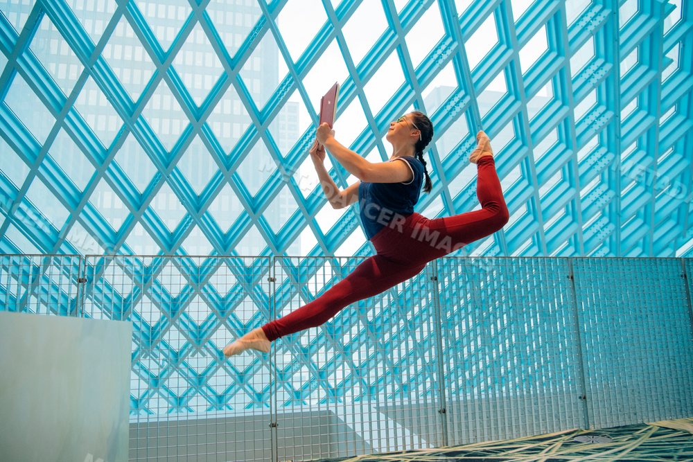Ballet dancer leaps and reads a book inside Seattle public library