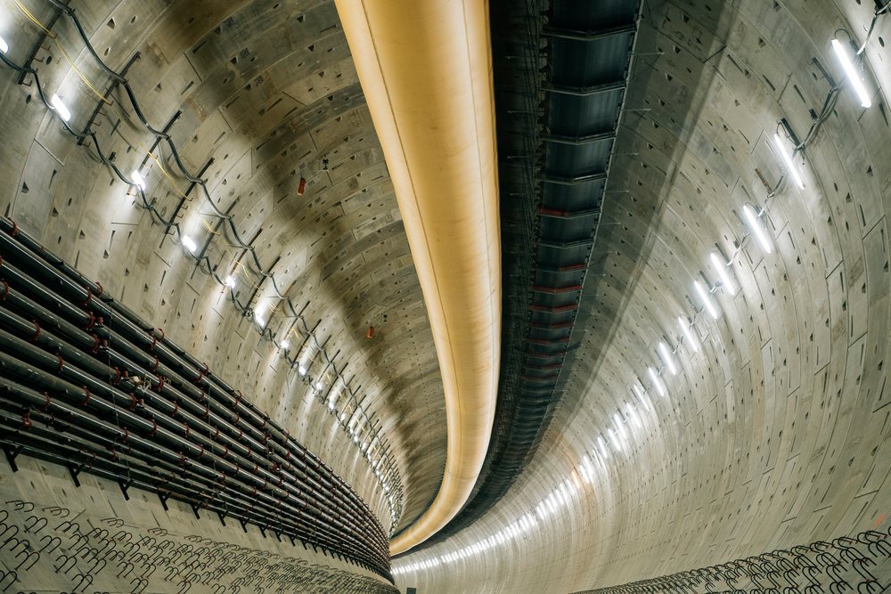 Interior view of a large concrete tunnel with pipework and ventilation ducts, Bertha, drilling, USA.