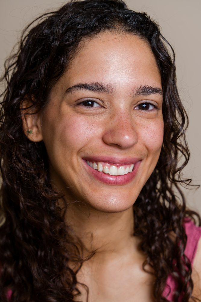 Woman with curly brown hair and freckles smiling in a beauty shoot, Spain.