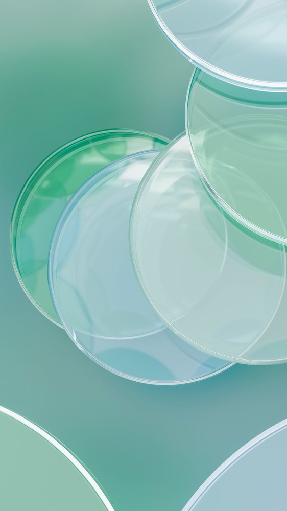 Transparent petri dishes stacked on a green surface in a clean laboratory setting.