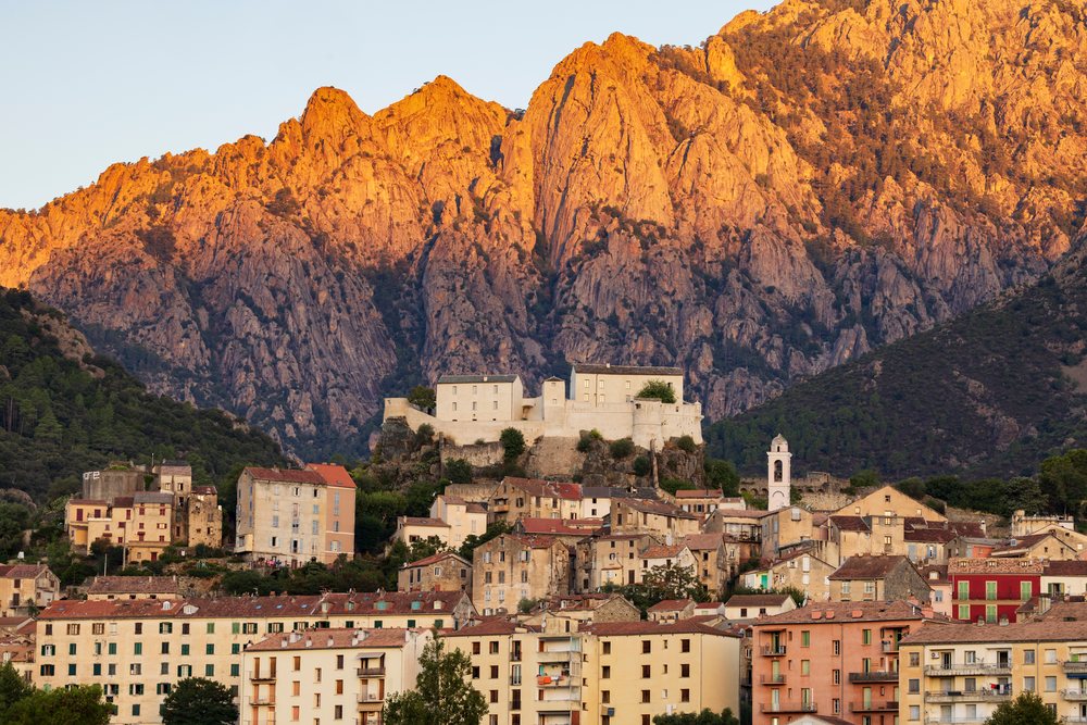 Sunrise illuminates rocky mountains and a fortress overlooking the village of, Travel Photography, Corte, Corsica, France.