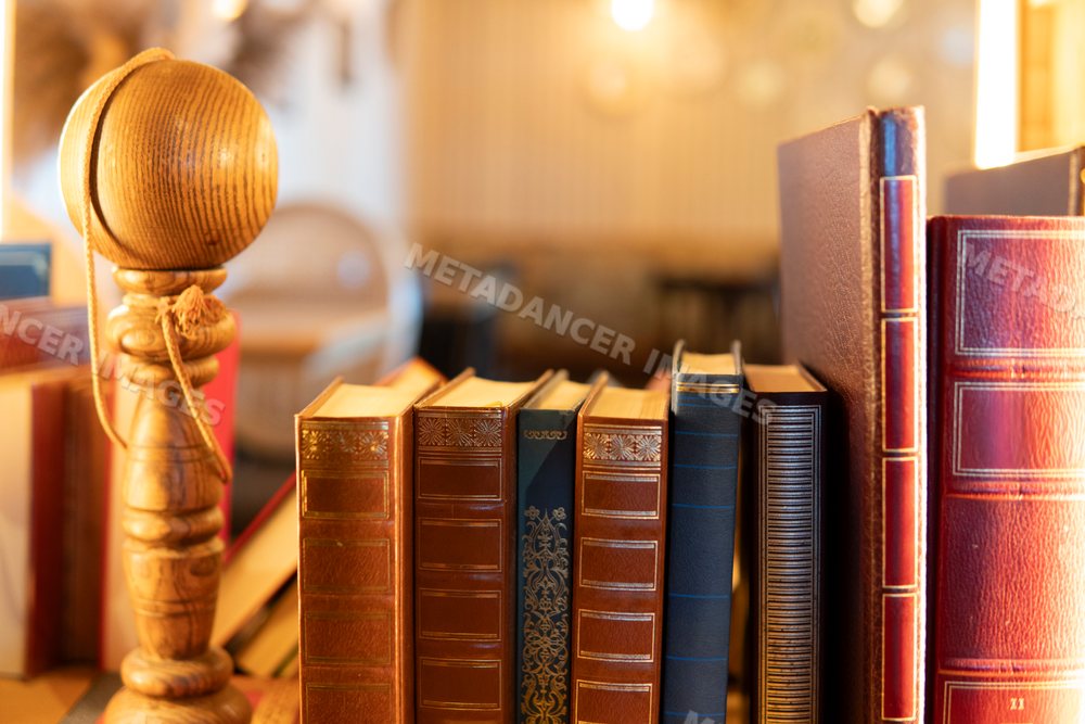 Antique leather-bound books displayed with a wooden spindle