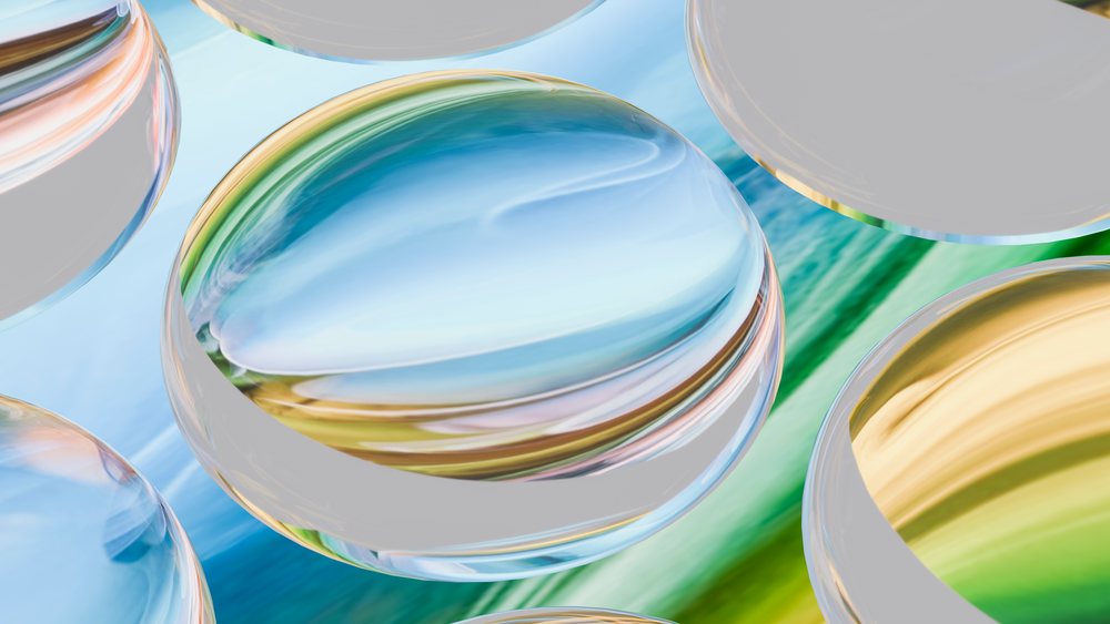 Digital 3D illustration of overlapping transparent glass spheres with colorful blue, green, and yellow reflections.