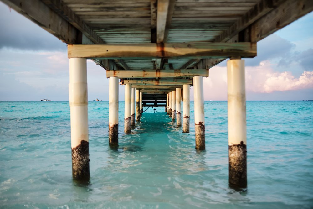 View beneath a wooden pier over clear ocean water