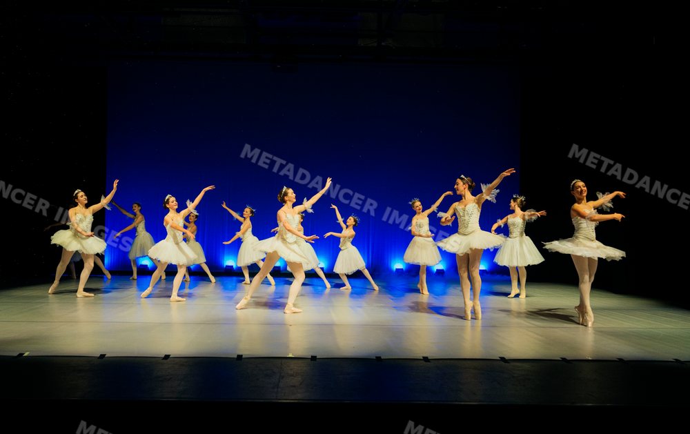 Ballet dancers perform a holiday-themed ballet on stage in white tutus
