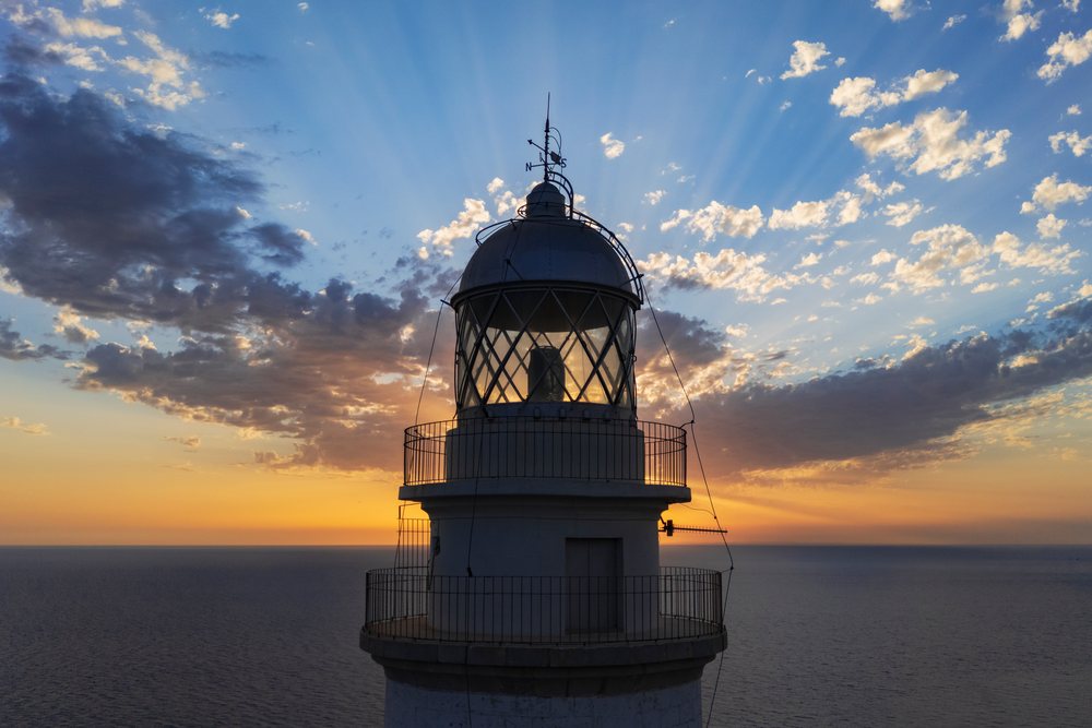 Sunrise over the Far de Formentor Lighthouse tower with weather vane, ocean, and partly cloudy sky on Mallorca's Cap de Formentor, Landscape, Lifestyle, Polença, Spain.