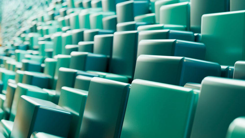 Rows of empty green stadium seats arranged in a tiered configuration at a large sports or event venue.