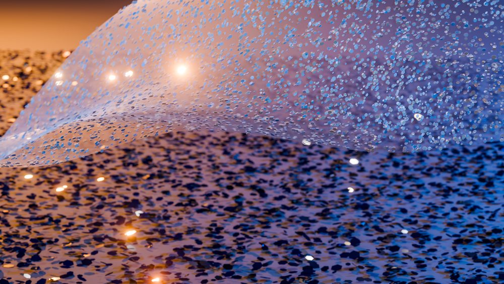 Blue sequined fabric with sparkling glitter creating a shimmering textured surface.