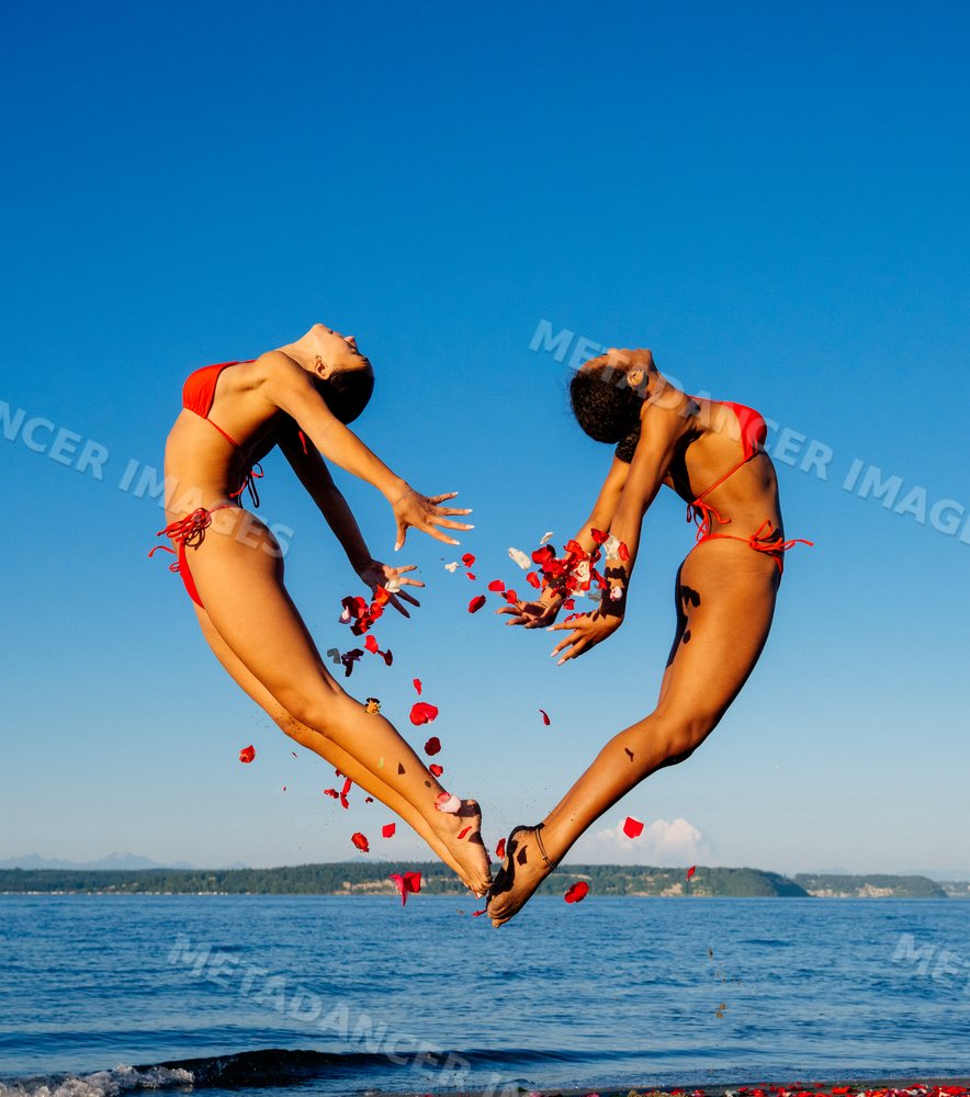 Two women performing partner acrobatic yoga on a beach in WA, USA
