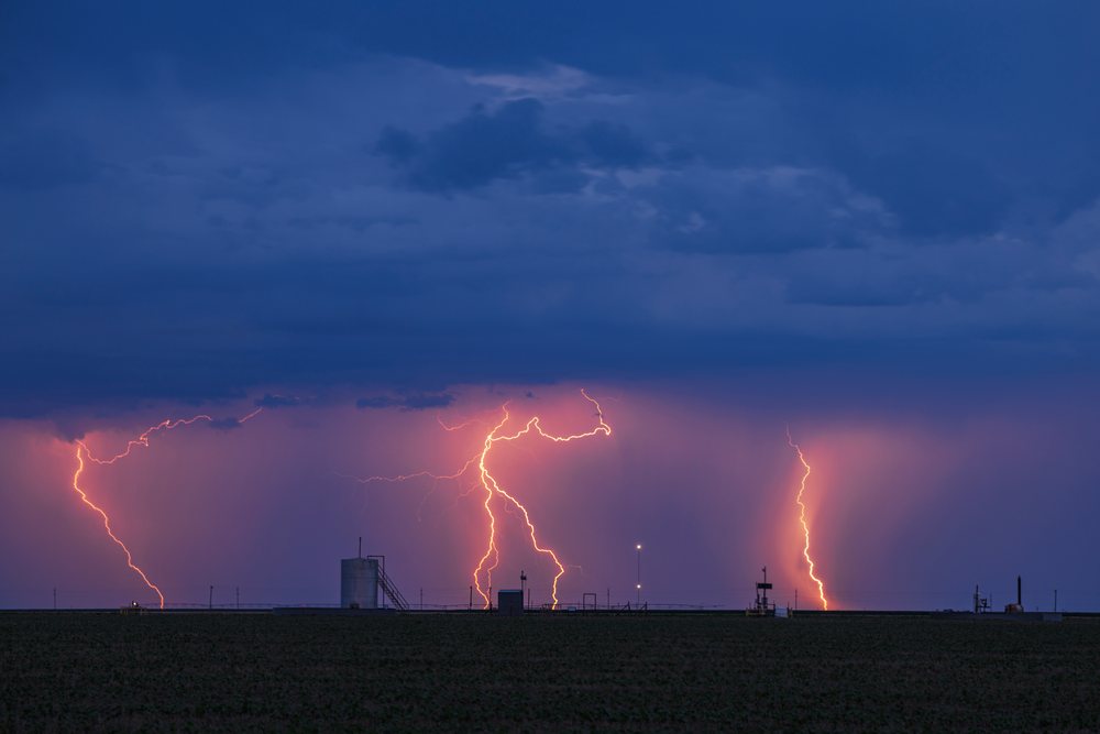 Lightning bolts strike over rural farm fields under dark storm clouds at twilight, Storm Chasing, Weather, Environmental issues, Perryton, Texas, USA.