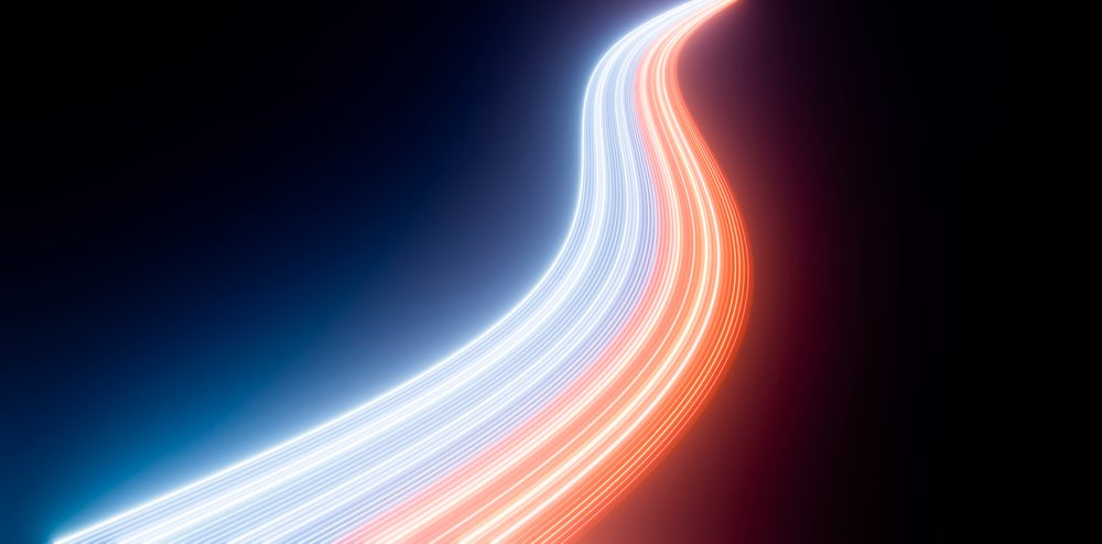 Curved blue and red neon light trails streak dynamically across a dark background with motion blur.
