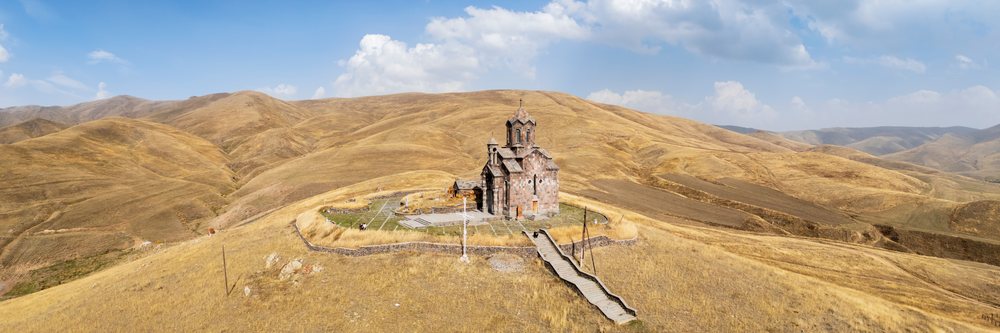 St Sarkis Church made of stone with a cross on top stands on a hilltop, Tsakhunk, Armenia.