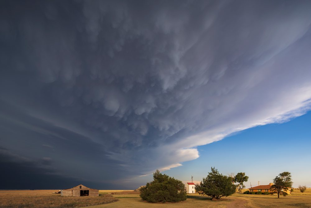 Storm clouds advance over a rural homestead with barn and houses in open fields, Storm Chasing, Weather, Environment, Johnson City, Kansas, USA.