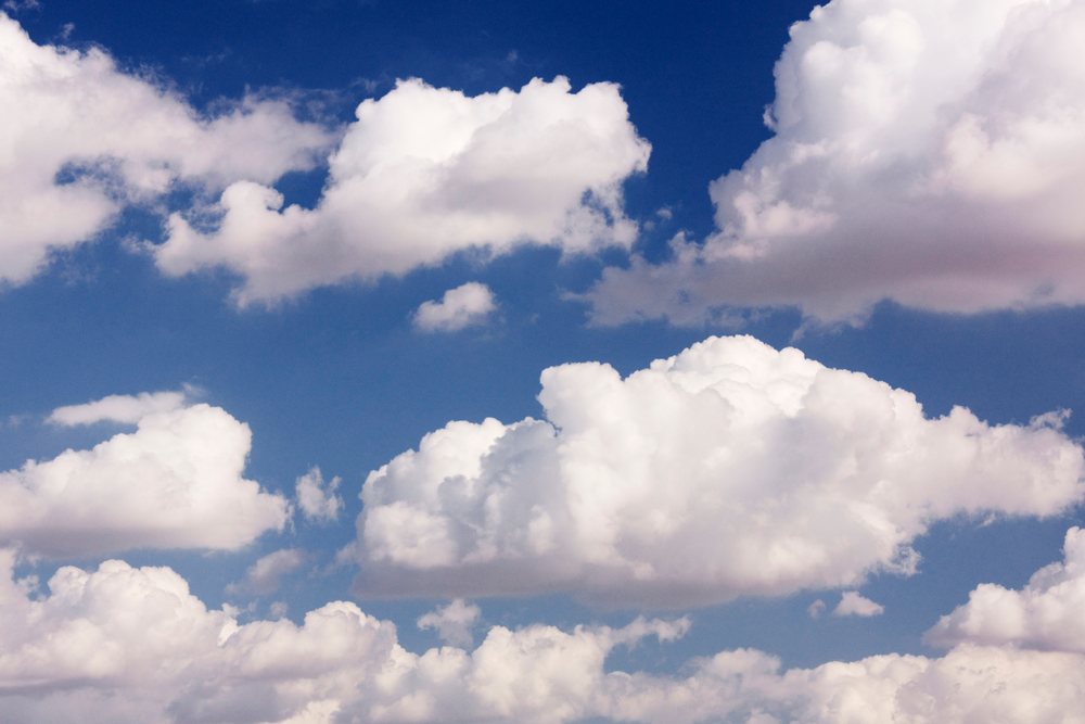 White cumulus clouds scattered across a clear blue daytime sky under natural sunlight.