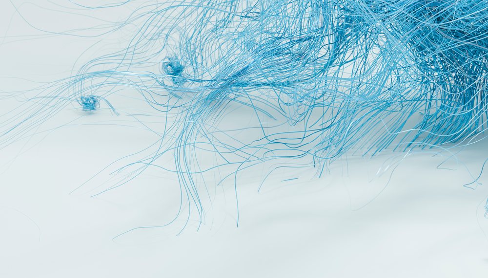 Blue fine threads tangled and clustered on a soft, light background.