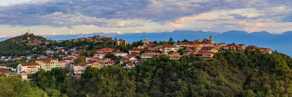 Sunrise over the town of Sighnaghi on a hill with red-roofed buildings and the snow-capped Caucasus Mountains in the background, Skylines, Georgia.