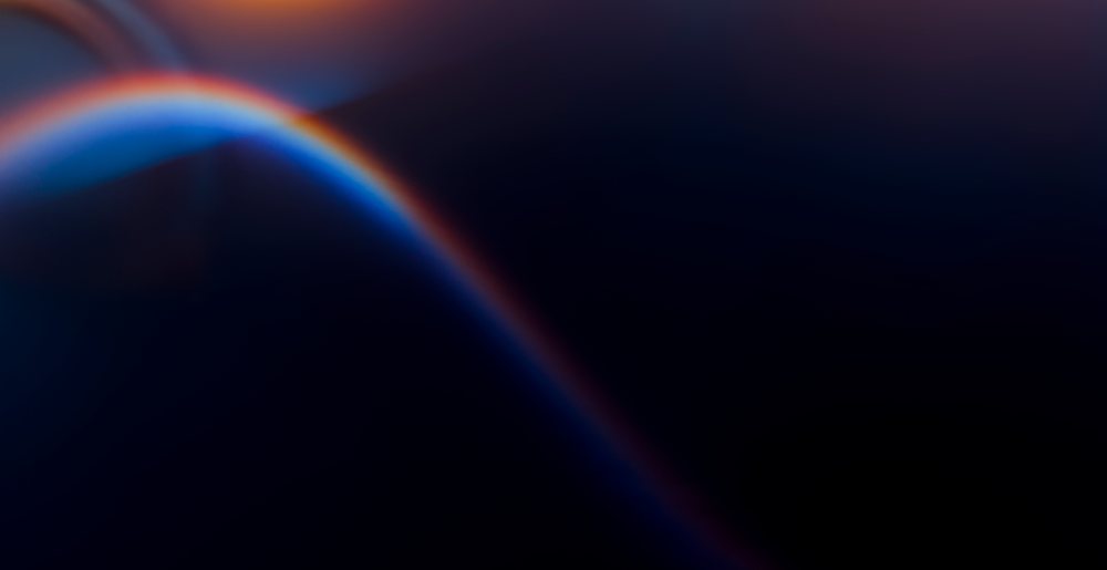 Abstract digital illustration featuring a smooth curved gradient transitioning from blue to orange on a dark background.